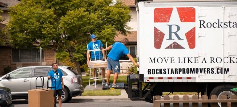 3 Movers downtown Dallas–Fort Worth metroplex loading a moving truck on the street