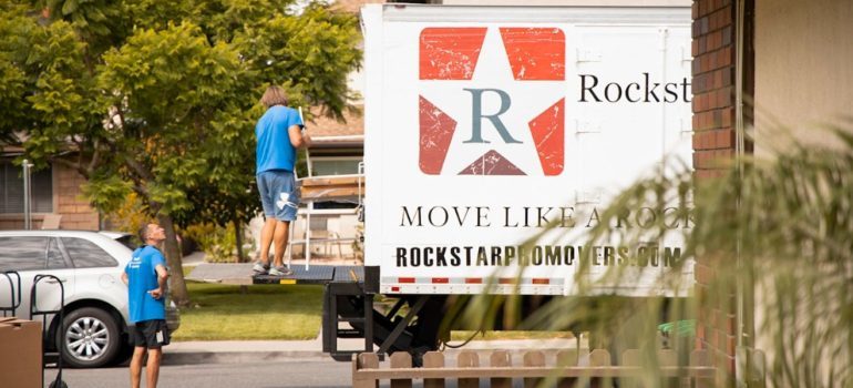 Two movers loading furniture onto Rockstar moving truck